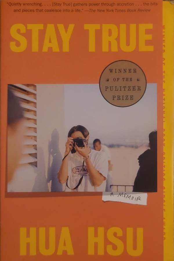 Cover of the memoir 'Stay True' by Hua Hsu. Features a picture of a young person holding a camera and snapping a picture and sticker indicating that it is a Pulitzer Prize winner.