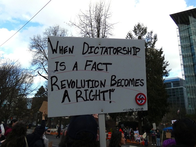 a casual ramble about black holes body image with a woman carrying a sign that reads a quote by victor hugo; "when dictatorship is a fact, revolution becomes a right"