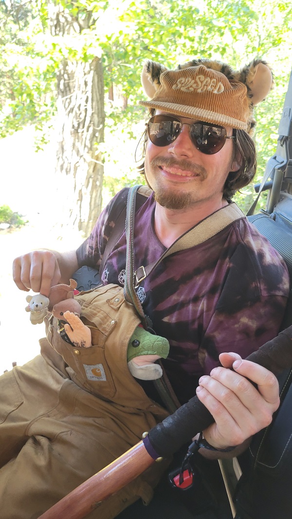 Man in suspenders with many plush animals posing in ATV.
