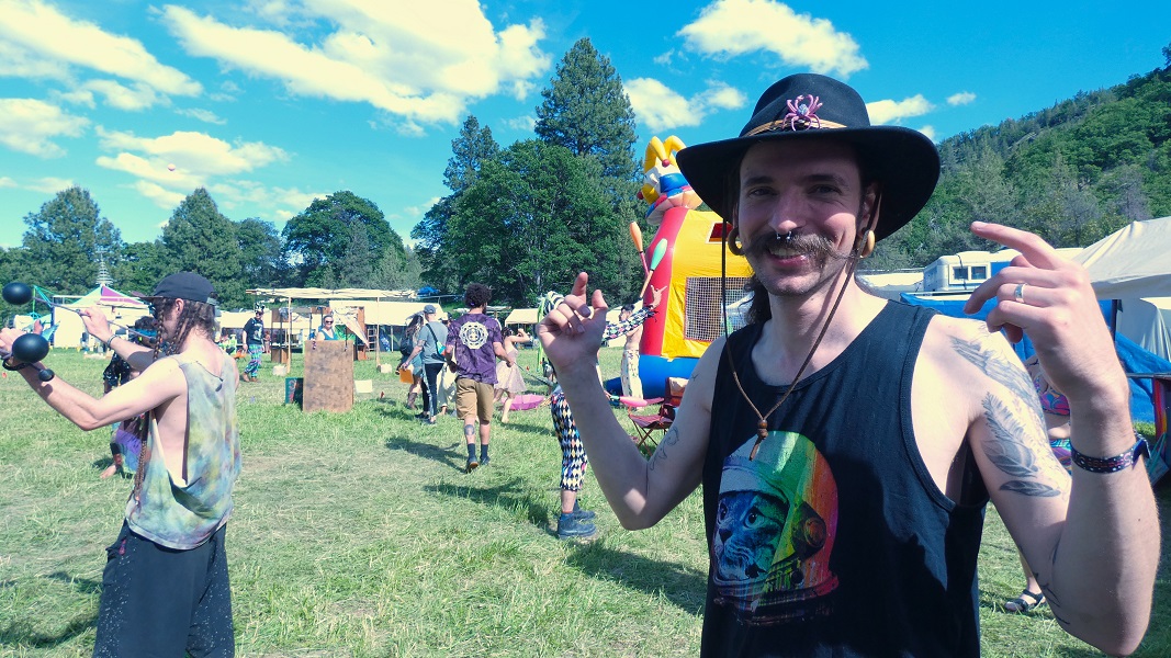 Man dancing and smiling in front of bouncy castle.