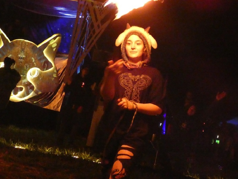 Woman spinning rope dart in fire circle.