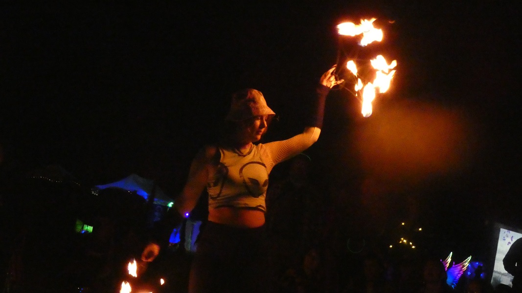 Woman dancing with fans in the fire circle.