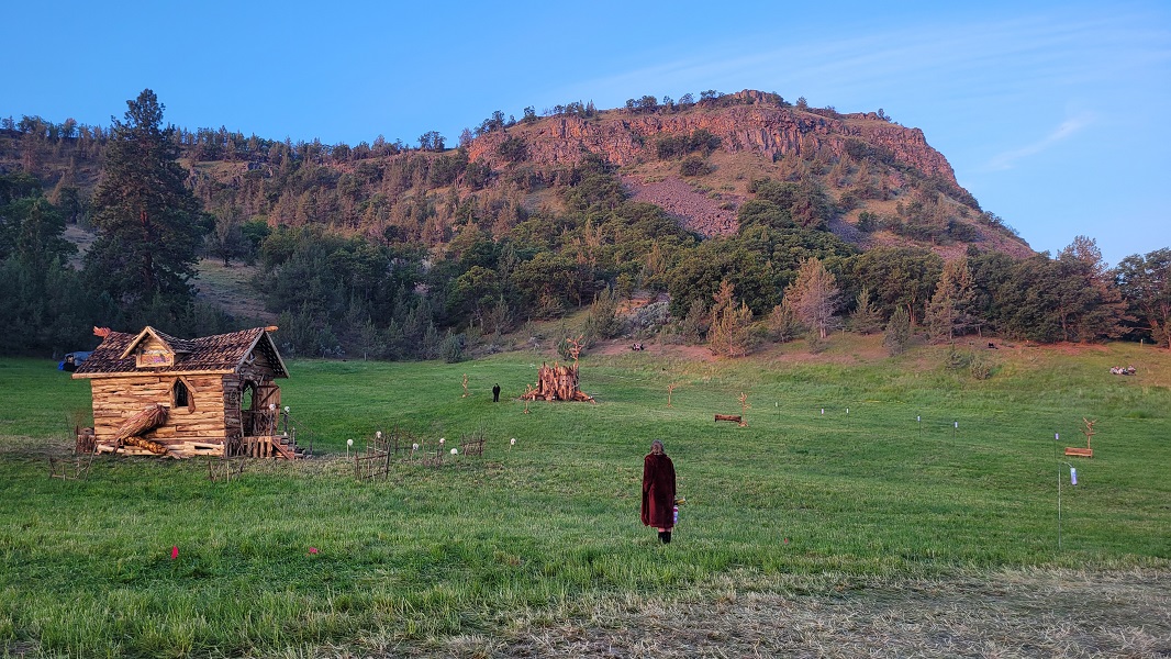 Woman stands in field as sun rises over the hills.