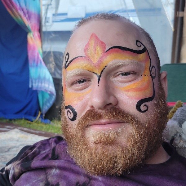 Man with face painted in the shape of flames and curly black lines.